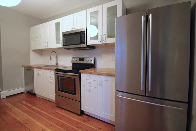 kitchen with white cabinetry, appliances with stainless steel finishes, butcher block counters, and sink