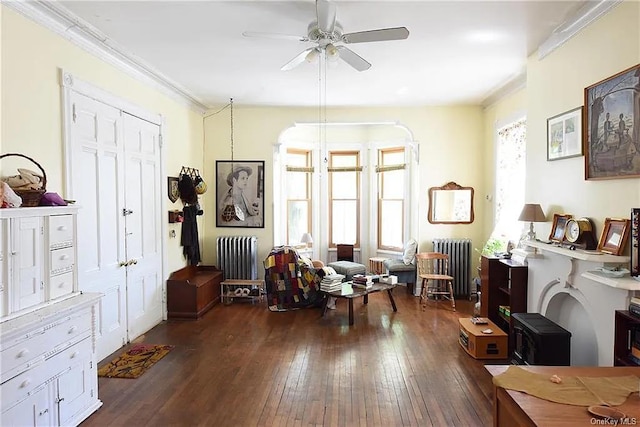 sitting room with radiator, crown molding, dark wood-type flooring, and ceiling fan