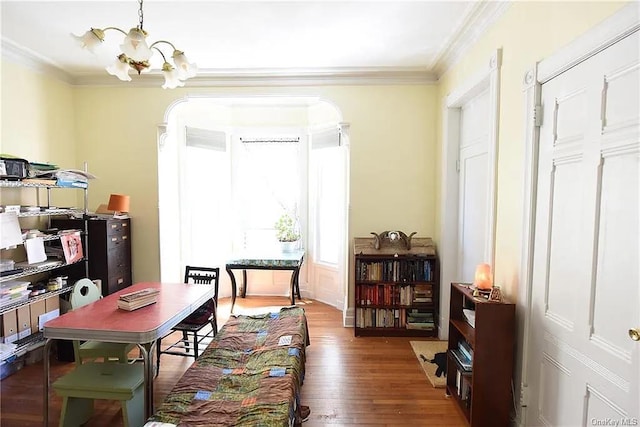 sitting room featuring an inviting chandelier, crown molding, and dark wood-type flooring