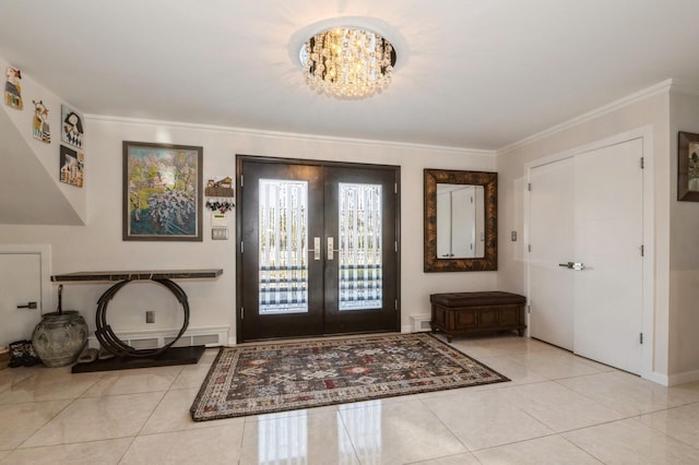 tiled foyer with crown molding, a notable chandelier, and french doors