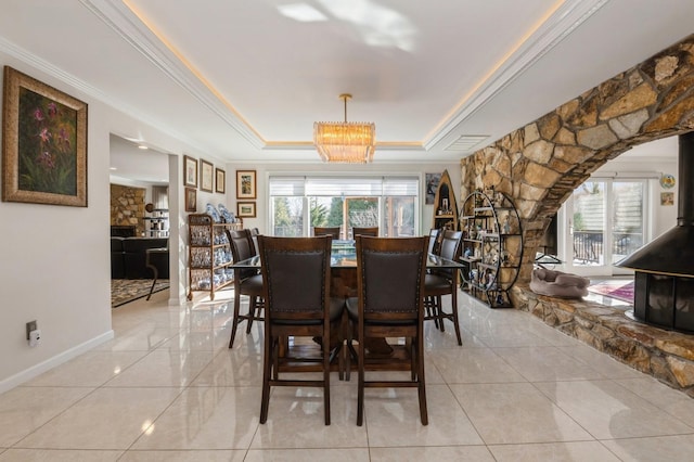 tiled dining area with a tray ceiling and ornamental molding