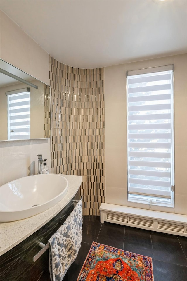 bathroom featuring plenty of natural light, a baseboard heating unit, tile walls, and tile patterned floors