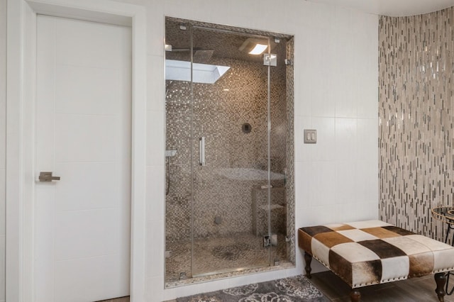 bathroom featuring a shower with door and tile walls