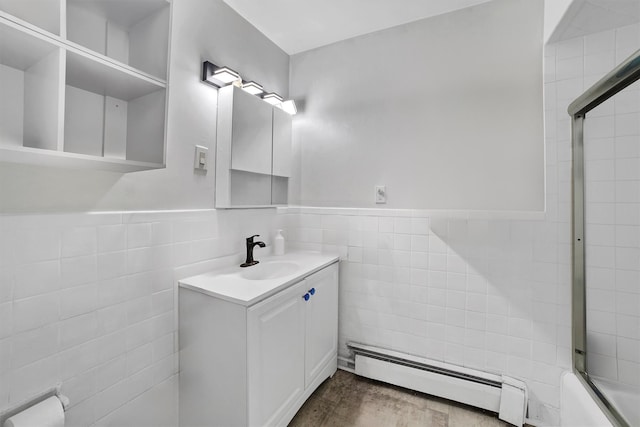 bathroom featuring a baseboard radiator, vanity, bath / shower combo with glass door, and tile walls