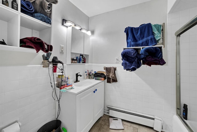 bathroom with a baseboard radiator, vanity, bath / shower combo with glass door, and tile walls