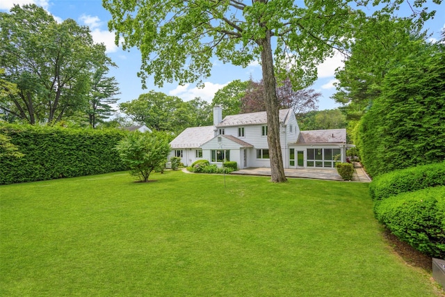 18 Kent Rd, Scarsdale, NY 10583 - rear view of house with a sunroom, a chimney, a lawn, and a patio