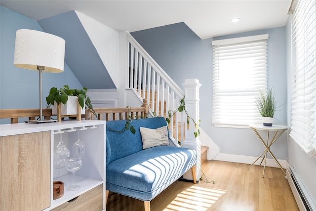 sitting room with a healthy amount of sunlight, light hardwood / wood-style flooring, and a baseboard heating unit