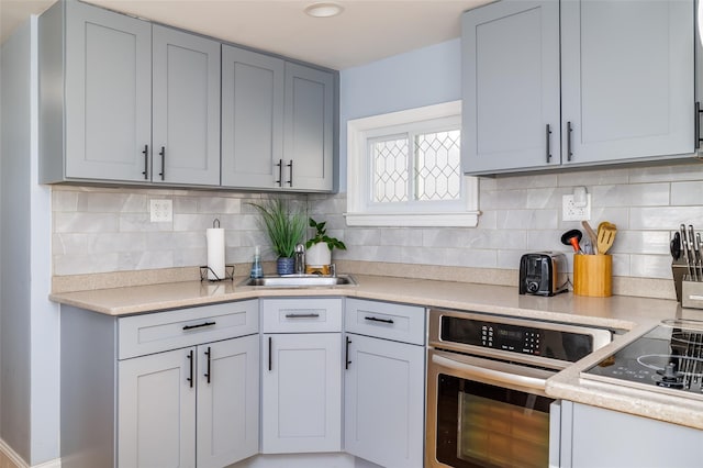 kitchen with tasteful backsplash, sink, oven, and black electric stovetop