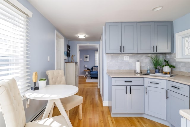 kitchen featuring decorative backsplash, plenty of natural light, baseboard heating, and light wood-type flooring