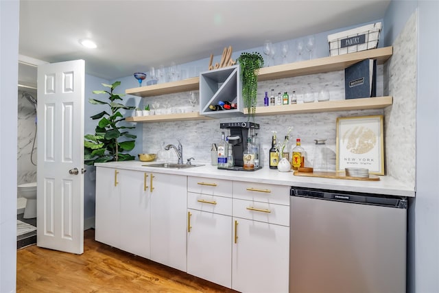 bar with sink, tasteful backsplash, light wood-type flooring, dishwasher, and white cabinets