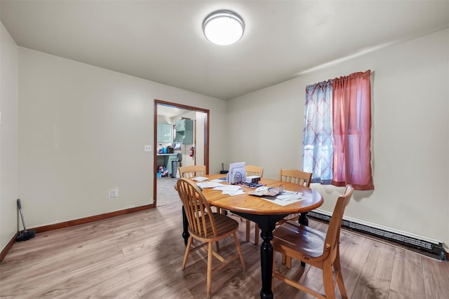 dining room featuring a baseboard heating unit and light hardwood / wood-style floors