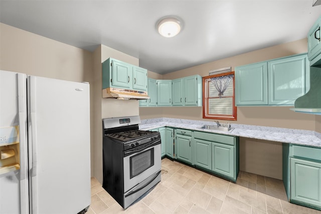 kitchen with gas stove, light stone countertops, white fridge with ice dispenser, and sink