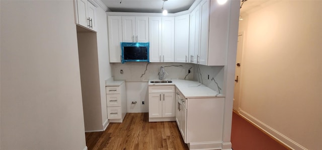 kitchen with decorative backsplash, sink, white cabinets, and light hardwood / wood-style flooring