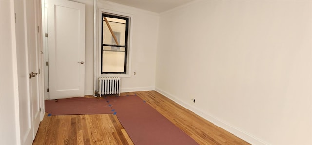 spare room with light hardwood / wood-style flooring, radiator heating unit, and ornamental molding