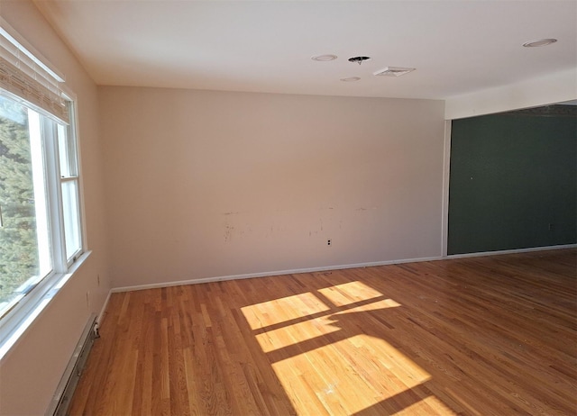 spare room featuring a baseboard heating unit and light hardwood / wood-style flooring