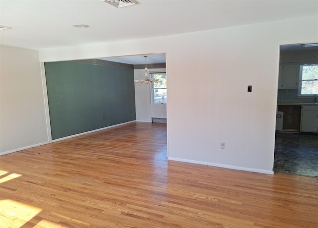 empty room with wood-type flooring and a notable chandelier