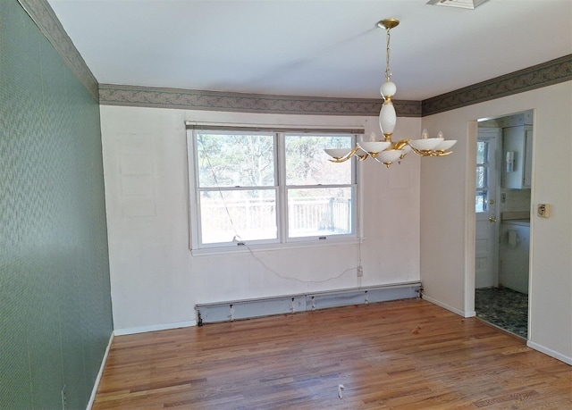 empty room featuring a notable chandelier, wood-type flooring, and a baseboard heating unit