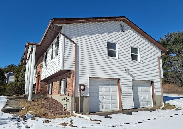 snow covered property with a garage