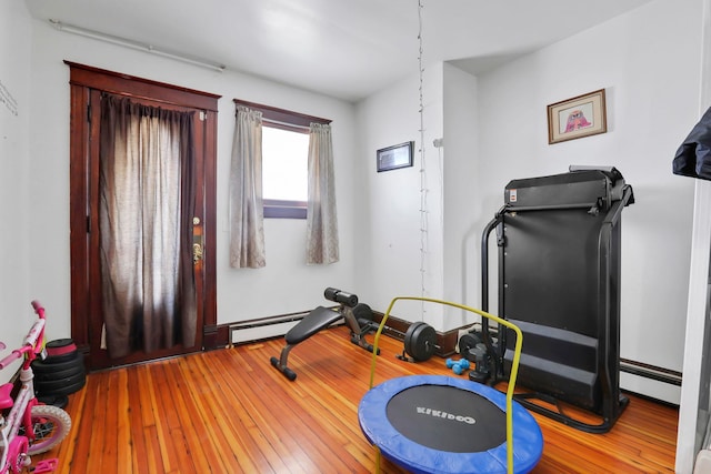 exercise area with wood-type flooring and a baseboard radiator