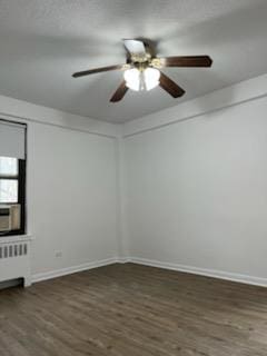 empty room with radiator, dark hardwood / wood-style floors, and ceiling fan