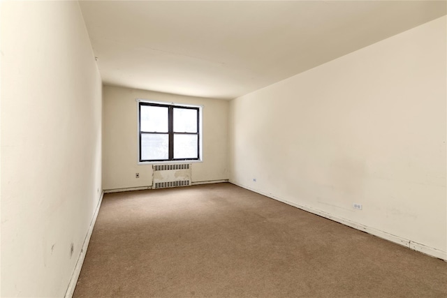 carpeted spare room featuring radiator heating unit