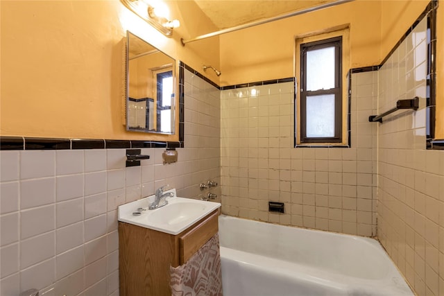 bathroom with vanity, tiled shower / bath combo, and tile walls