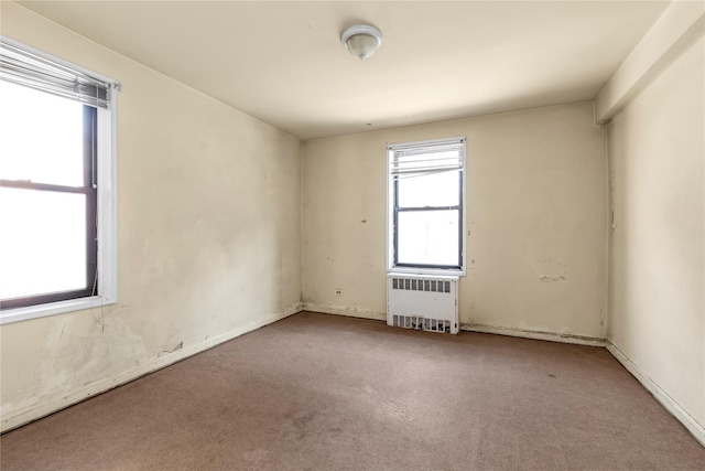 empty room featuring radiator heating unit and carpet flooring