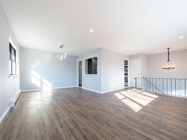 unfurnished room featuring a baseboard heating unit, dark hardwood / wood-style floors, and a notable chandelier