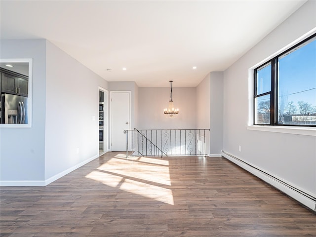 empty room featuring a notable chandelier, dark hardwood / wood-style floors, and a baseboard heating unit