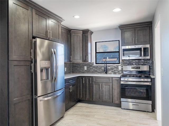 kitchen featuring stainless steel appliances, sink, dark brown cabinetry, and decorative backsplash