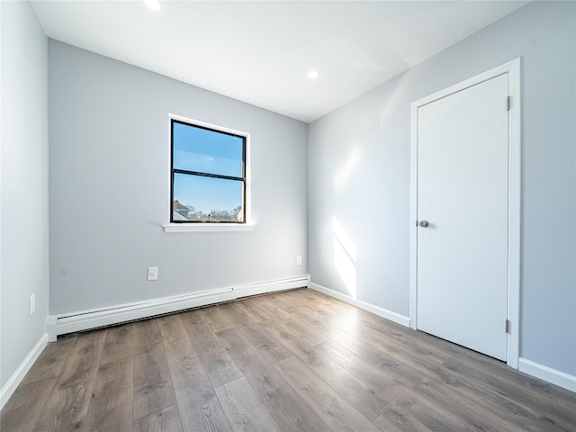 unfurnished room featuring baseboard heating and light wood-type flooring