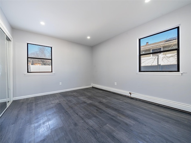 spare room featuring dark hardwood / wood-style flooring and a baseboard heating unit