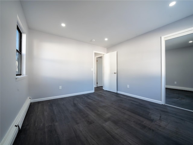 unfurnished bedroom with a baseboard radiator and dark hardwood / wood-style floors