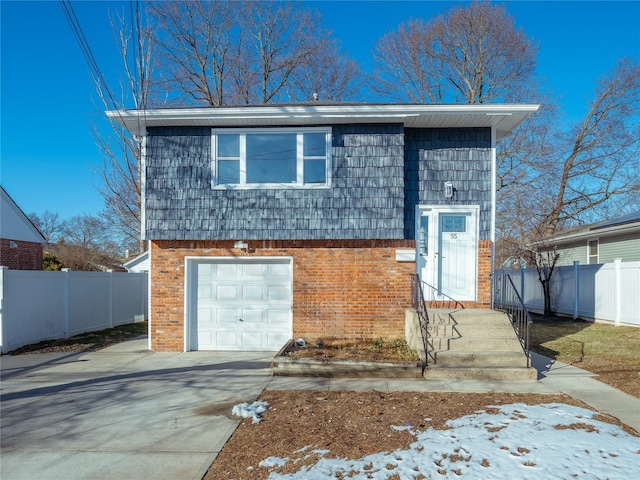 view of front of house with driveway, an attached garage, fence, and brick siding