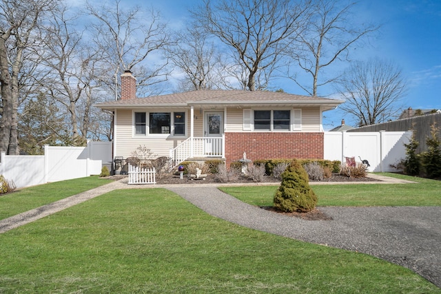 view of front facade featuring brick siding, fence, a chimney, and a front lawn