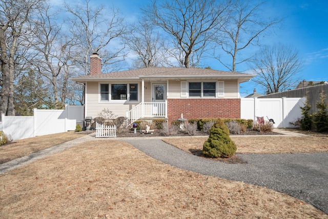 view of front of house with brick siding, gravel driveway, fence, and a gate