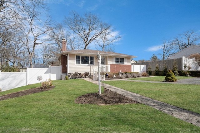 view of front of property featuring a chimney, fence, a front lawn, and brick siding