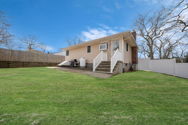 rear view of house featuring a patio area, a fenced backyard, a chimney, and a lawn