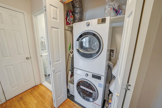 laundry room with laundry area, light wood finished floors, and stacked washer / drying machine