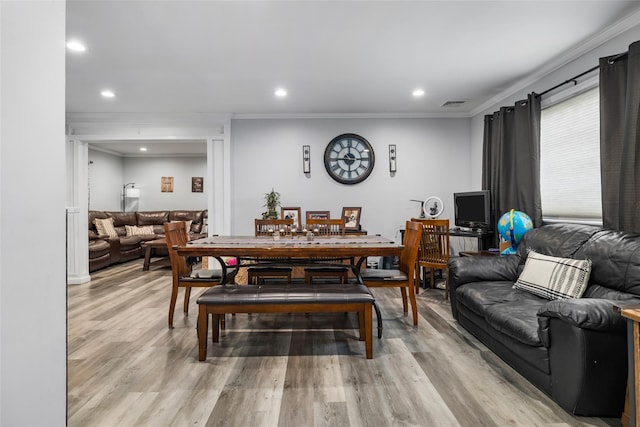 dining space with crown molding and light hardwood / wood-style flooring