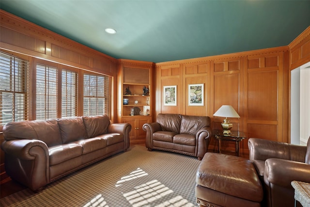 living room featuring ornamental molding, light carpet, built in features, and wooden walls