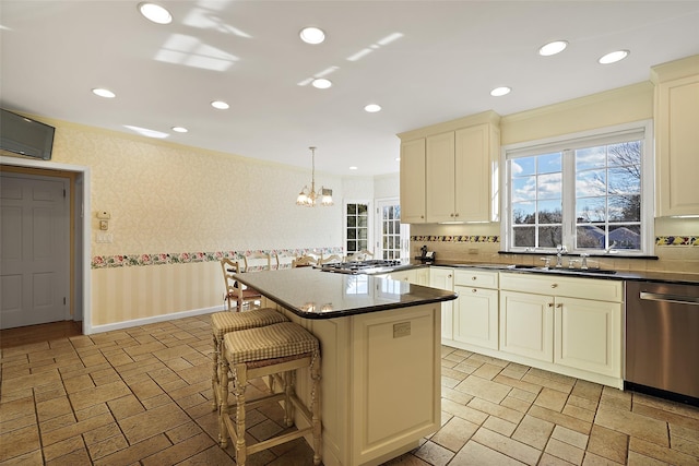 kitchen featuring sink, hanging light fixtures, stainless steel appliances, ornamental molding, and a kitchen bar