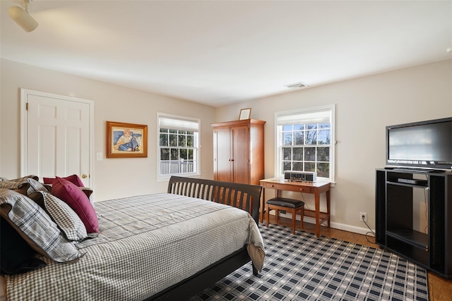 bedroom with multiple windows and hardwood / wood-style flooring