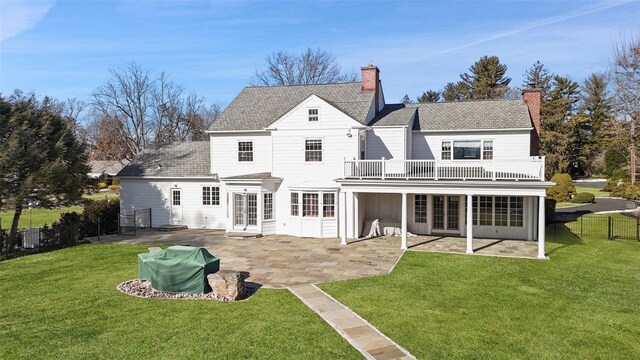 rear view of property with a balcony, a yard, and a patio area