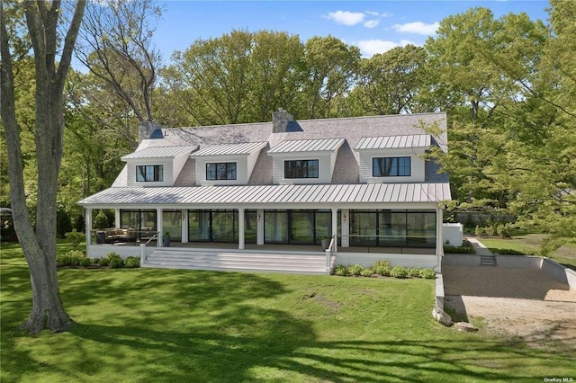 back of property with a standing seam roof, a yard, and metal roof