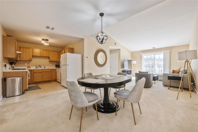 dining space featuring an inviting chandelier, light colored carpet, sink, and vaulted ceiling