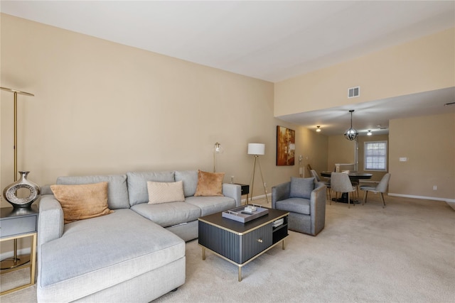 carpeted living room with an inviting chandelier