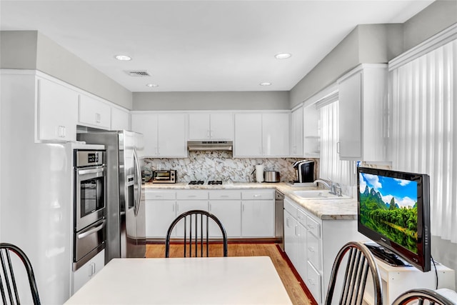 kitchen featuring white cabinetry, sink, decorative backsplash, and appliances with stainless steel finishes