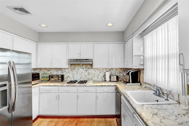 kitchen featuring white cabinetry, stainless steel appliances, sink, and decorative backsplash