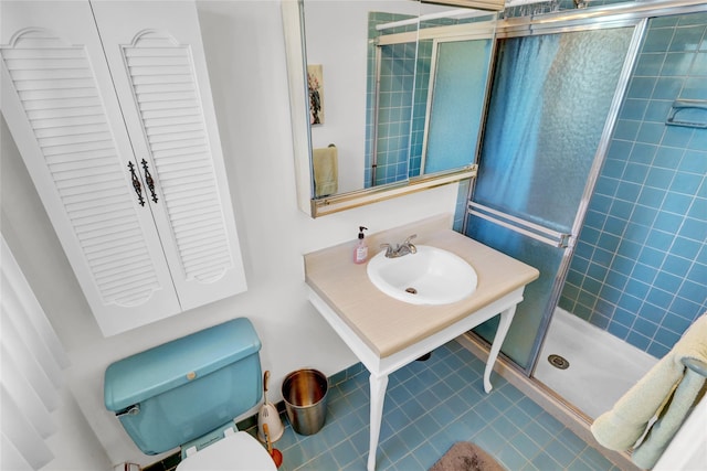 bathroom with an enclosed shower, sink, tile patterned floors, and toilet